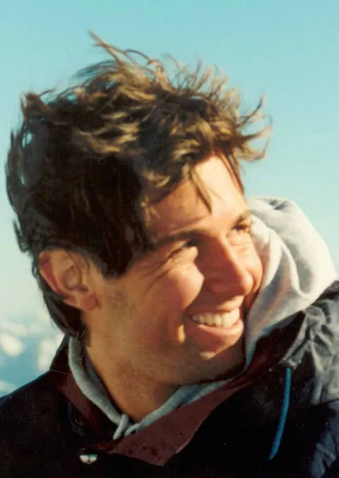 Guillermo Muzzio smiling, his hair in the wind on the mountain